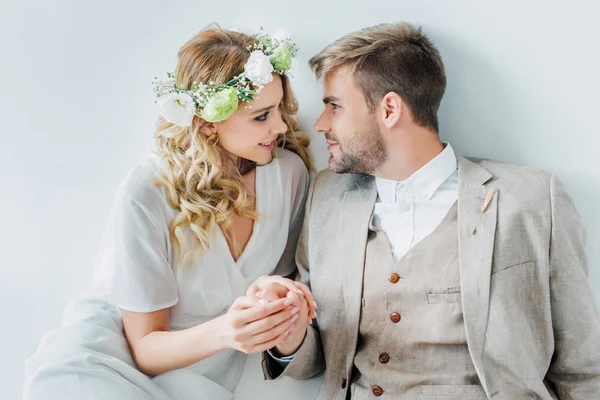 Attractive bride and handsome bridegroom holding hands and looking at each other — Stock Photo