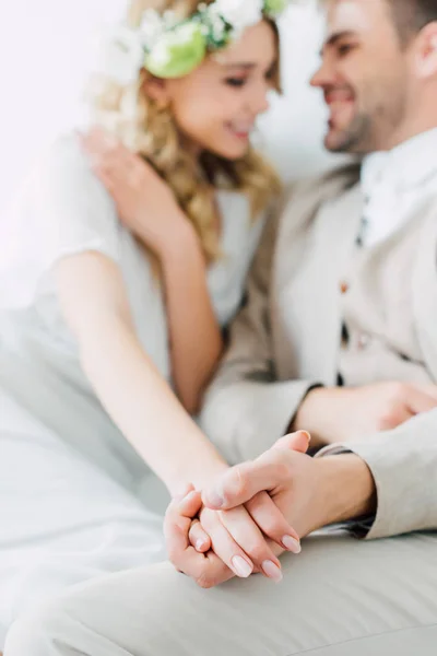 Enfoque selectivo de la novia en el vestido de novia y el novio de la mano - foto de stock