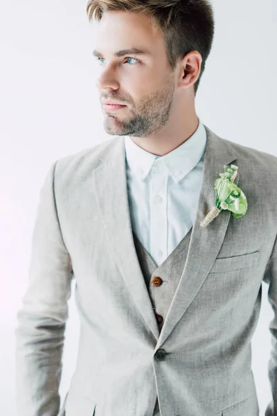 Novio guapo en traje con boutonniere floral mirando hacia otro lado aislado en gris - foto de stock