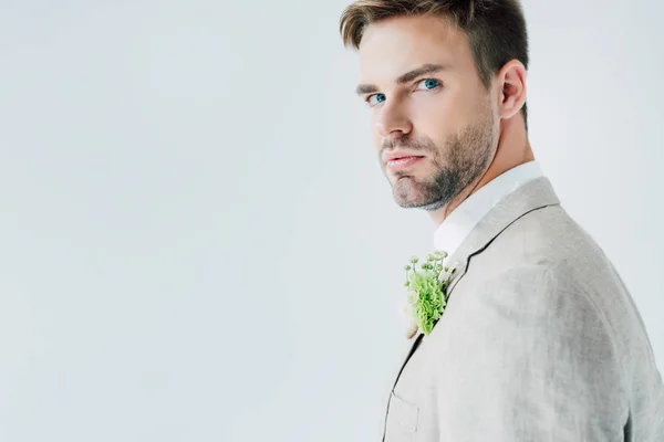 Schöner Bräutigam im Anzug mit geblümtem Boutonniere, der isoliert auf grau in die Kamera blickt — Stockfoto