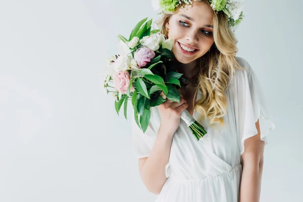 Noiva atraente em vestido de noiva e coroa segurando buquê isolado no branco — Fotografia de Stock