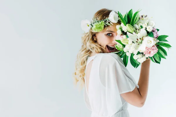 Noiva atraente em vestido de noiva e coroa segurando buquê isolado no branco — Fotografia de Stock