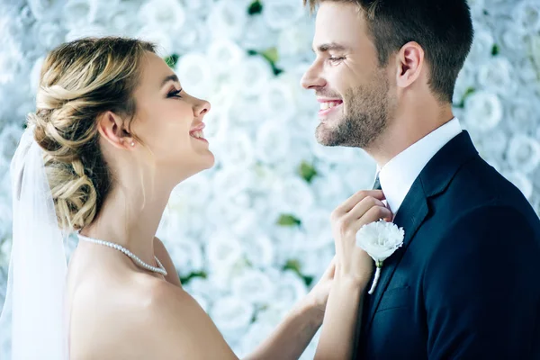 Привлекательная невеста и красивый жених улыбаются и смотрят друг на друга — стоковое фото