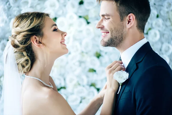 Attractive bride and handsome bridegroom smiling and looking at each other — Stock Photo