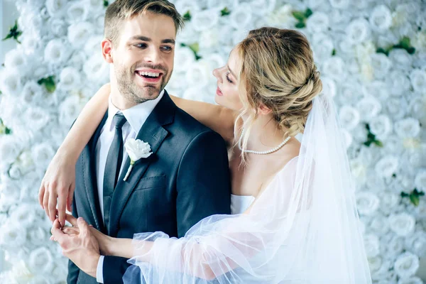 Attractive bride and handsome bridegroom smiling and looking at each other — Stock Photo