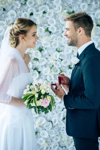 Vista lateral del novio haciendo propuesta a la novia en vestido de novia - foto de stock