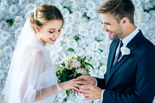 Bonito e sorridente noivo colocando anel de casamento no dedo — Fotografia de Stock