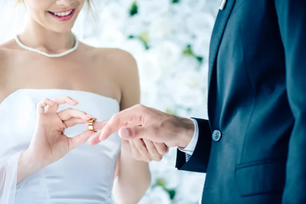 Vista recortada de la novia sonriente poniendo anillo de bodas en el dedo - foto de stock