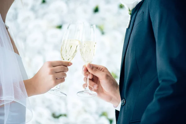 Vista recortada de novia y novio tintineo con copas de champán - foto de stock