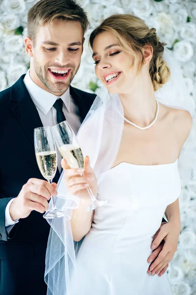 Mariée attrayante et beau marié souriant et cliquetis avec des verres de champagne — Photo de stock