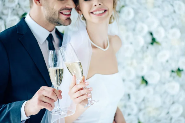 Vista recortada de novia y novio tintineo con copas de champán - foto de stock