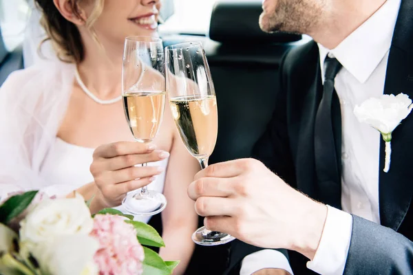 Vista recortada de novia y novio tintineo con copas de champán - foto de stock