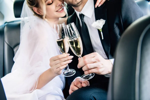 Cropped view of bride and bridegroom clinking with champagne glasses — Stock Photo