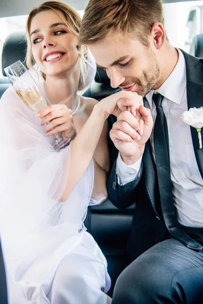 Beau marié en costume baisant la main de sa belle mariée — Photo de stock