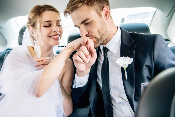 Beau marié en costume baisant la main de sa belle mariée — Photo de stock