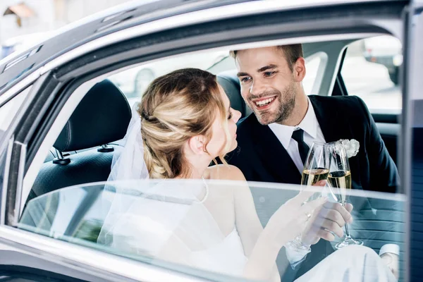 Attractive bride and handsome bridegroom clinking with champagne glasses — Stock Photo