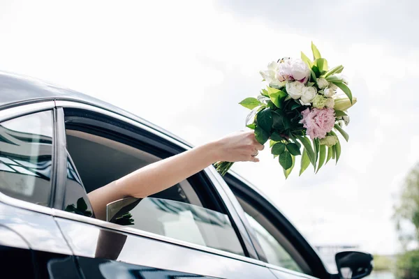 Cropped view of young adult bride holding holding bouquet — Stock Photo
