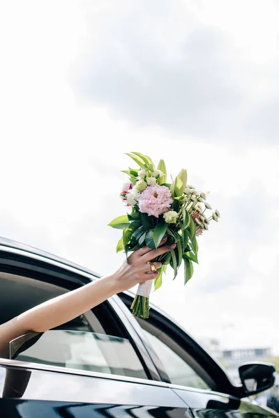 Cropped view of young adult bride holding holding bouquet — Stock Photo