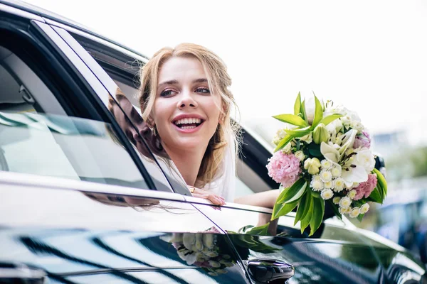 Attraktive und blonde Braut mit Blumenstrauß und Wegschauen — Stockfoto