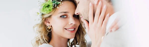 Panoramaaufnahme der attraktiven Braut und des hübschen Bräutigams, die sich umarmen und vereinzelt in die Kamera schauen — Stockfoto