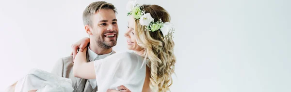 Panoramaaufnahme der attraktiven Braut und des hübschen Bräutigams, die einander lächelnd und isoliert auf Weiß betrachten — Stockfoto