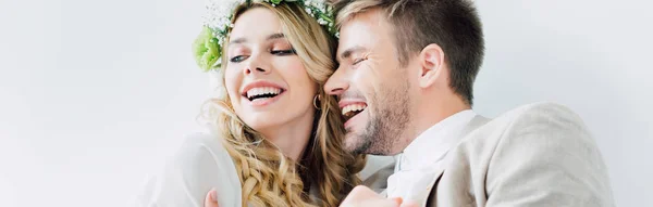 Tiro panorâmico de noiva atraente e belo noivo sorrindo e olhando para longe isolado no branco — Fotografia de Stock