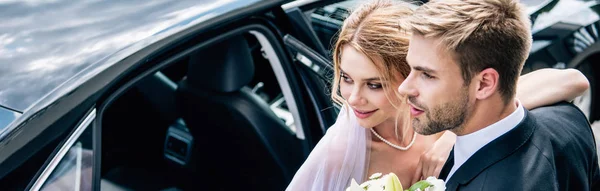 Panoramic shot of attractive bride and handsome bridegroom hugging outside — Stock Photo