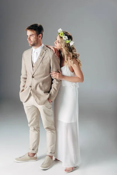 Braut in Brautkleid und Kranz umarmt hübschen Bräutigam im Anzug — Stockfoto