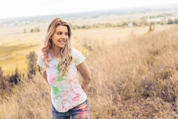 Jolie femme en t-shirt souriant et détournant les yeux à l'extérieur — Photo de stock