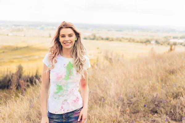 Atractiva mujer en camiseta sonriendo y mirando a la cámara - foto de stock