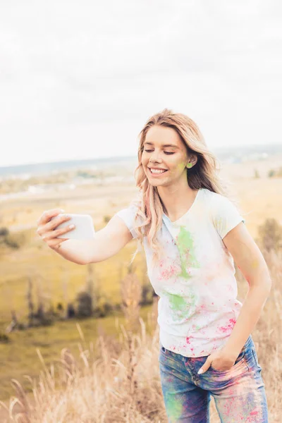 Attraktive Frau im T-Shirt lächelt und macht Selfie draußen — Stockfoto