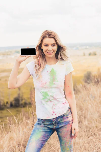 Attractive woman in t-shirt holding smartphone with blank screen — Stock Photo
