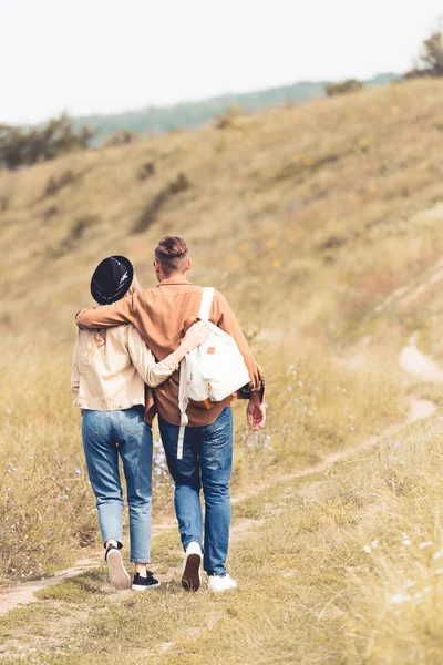 Vue arrière de la femme et de l'homme avec sac à dos étreignant à l'extérieur — Photo de stock