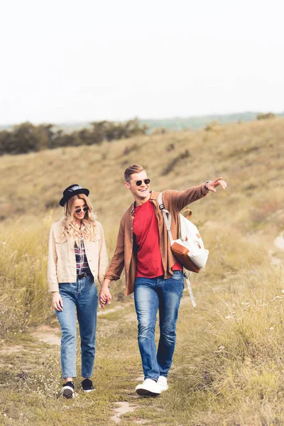 Bel homme pointant du doigt et marchant avec une femme attrayante — Photo de stock