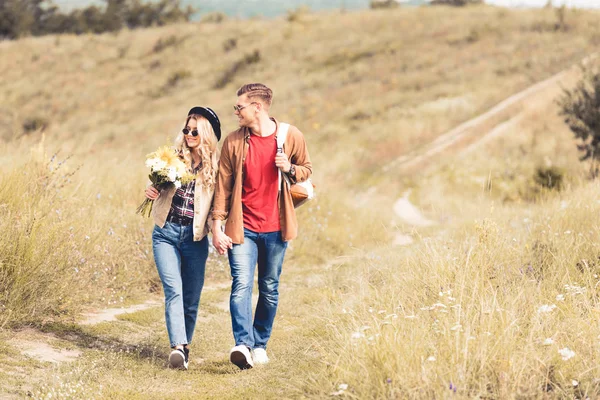 Attraktive Frau mit Strauß und schöner Mann lächelnd und Händchenhaltend — Stockfoto