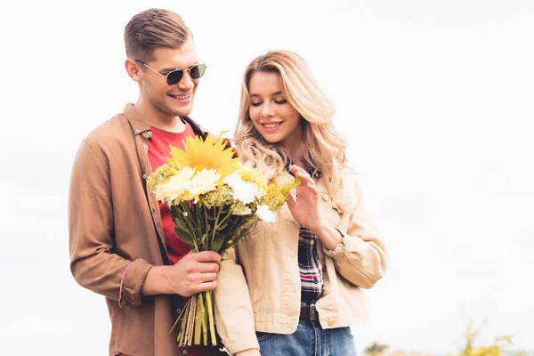 Bel homme dans des lunettes donnant bouquet à la femme blonde — Photo de stock