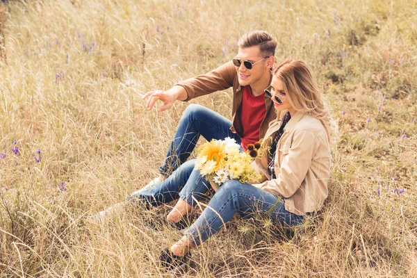 Mulher atraente com buquê e homem bonito apontando com o dedo — Fotografia de Stock