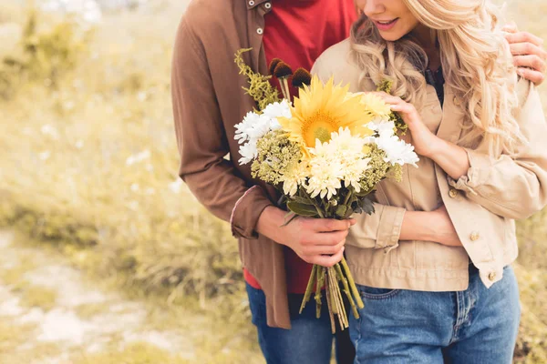 Cropped view of man in shirt giving bouquet to blonde woman — Stock Photo