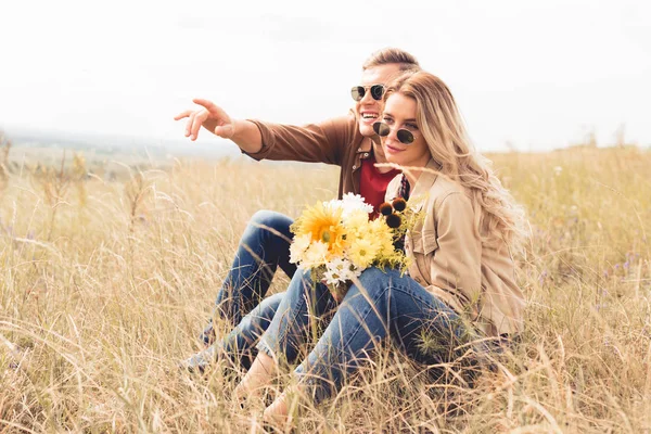 Attractive woman with bouquet and handsome man pointing with finger — Stock Photo
