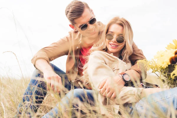 Attrayant femme avec bouquet et bel homme souriant et assis à l'extérieur — Photo de stock