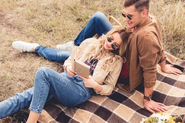 Atractiva mujer y hombre guapo sonriendo y leyendo libro - foto de stock