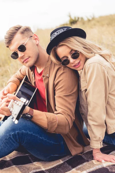 Homem bonito tocando guitarra acústica e mulher atraente abraçando ele — Fotografia de Stock