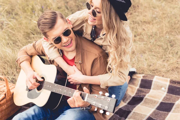 Guapo hombre tocando la guitarra acústica y atractiva mujer abrazándolo — Stock Photo