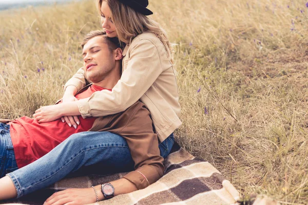 Schöner Mann und attraktive Frau umarmen und sitzen auf einer Decke — Stockfoto