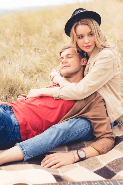 Homem bonito e mulher atraente abraçando e sentado em cobertor — Fotografia de Stock