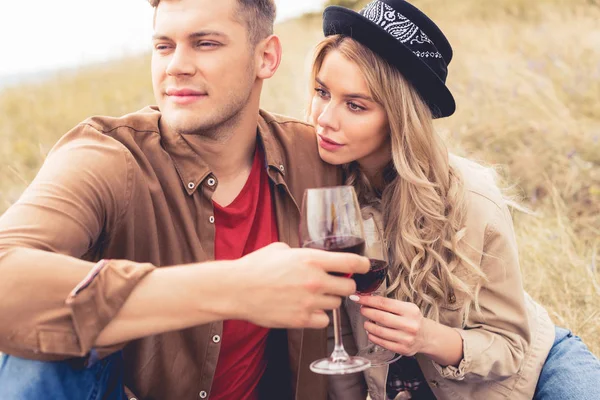 Hombre guapo y atractiva mujer en sombrero sosteniendo copas de vino - foto de stock