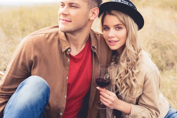 Handsome man looking away and attractive woman in hat holding wine glass — Stock Photo