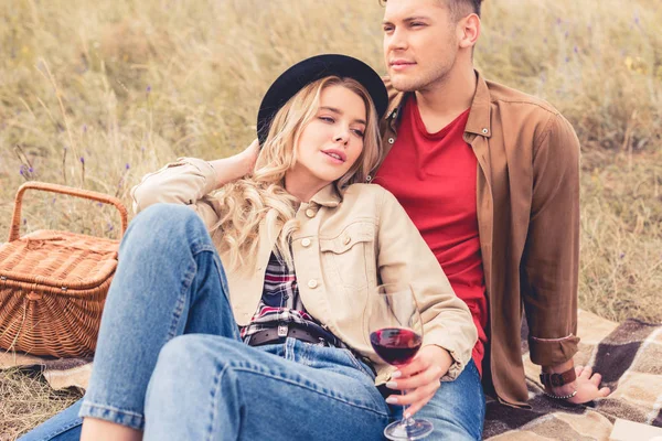 Hombre guapo mirando hacia otro lado y mujer atractiva sosteniendo copa de vino - foto de stock