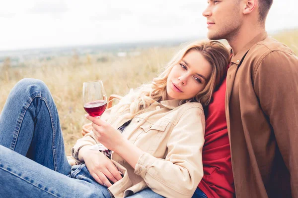 Hombre guapo mirando hacia otro lado y mujer atractiva sosteniendo copa de vino - foto de stock