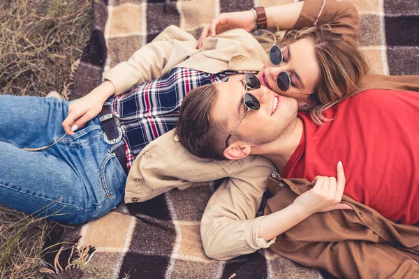 Mujer atractiva y hombre guapo abrazo y acostado en manta - foto de stock